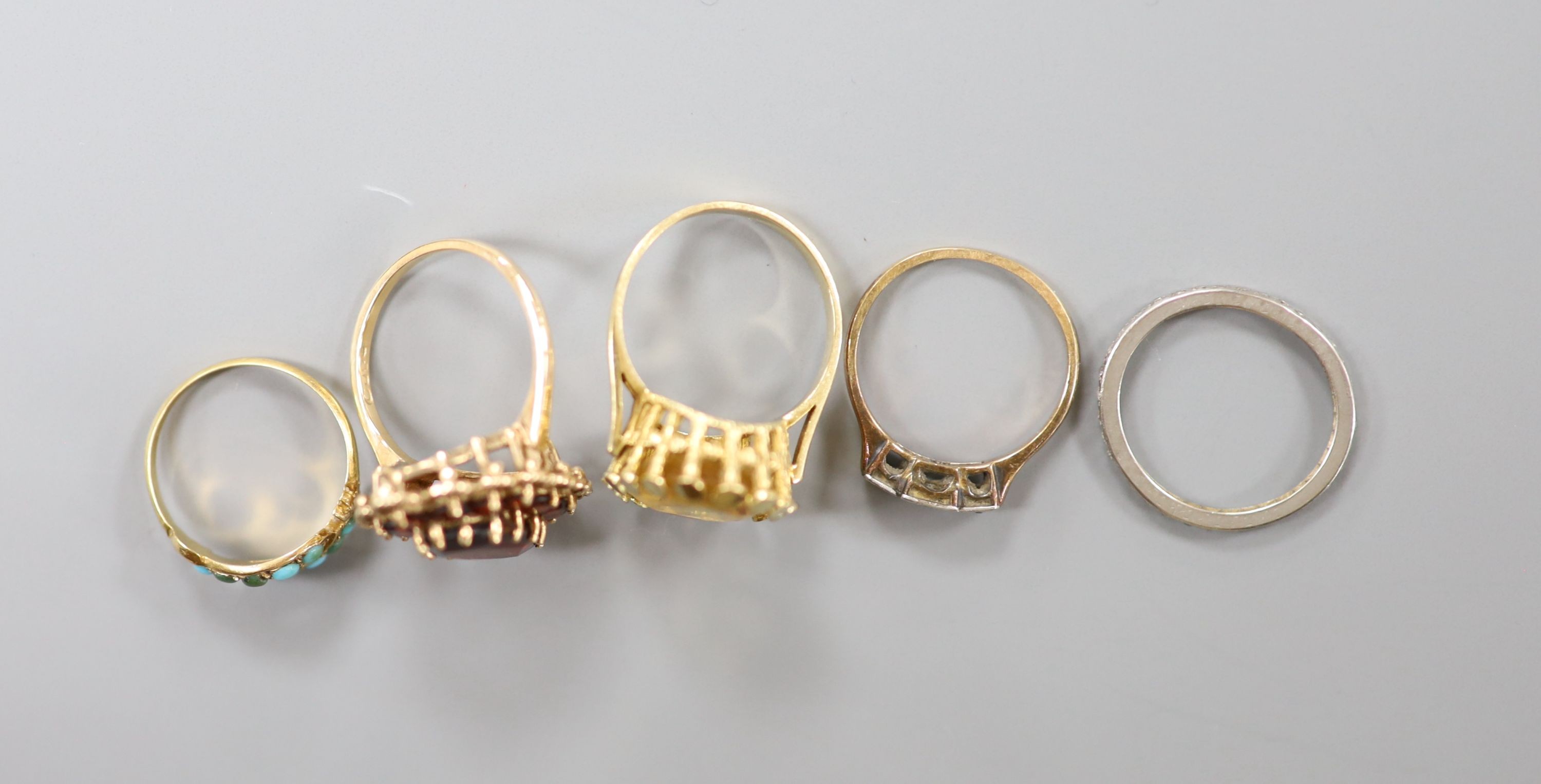 Three assorted 9ct gold and gem set rings including garnet and citrine, gross 11.4 grams, a yellow metal and turquoise ring, gross 1.4 grams and a white metal and diamond chip set full eternity ring, gross 2.2 grams.